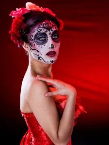 A woman dressed as Catrina for Day of the Dead. She has a face painted like a skeleton and a beautiful red dress.
