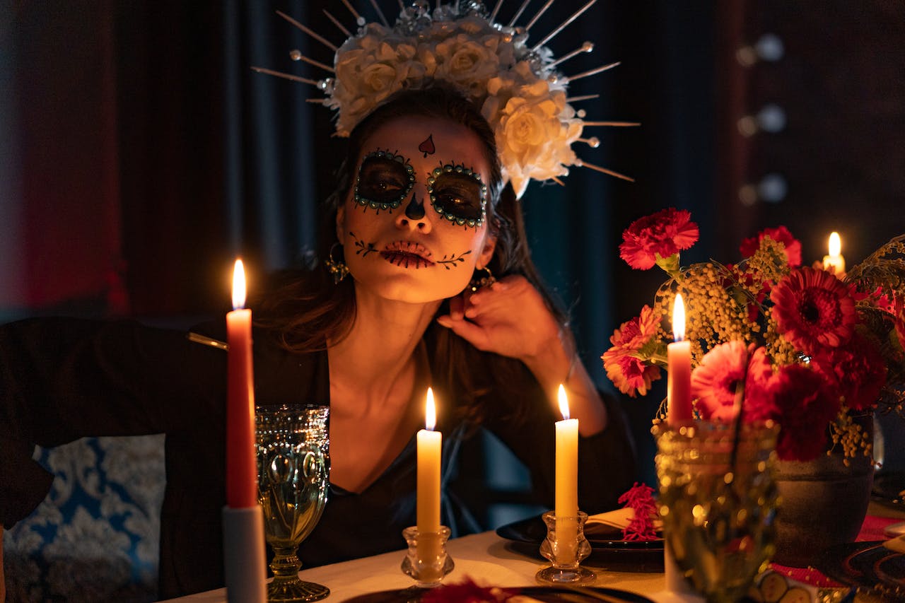 A woman with a painted face celebrating Day of the Dead with candles
