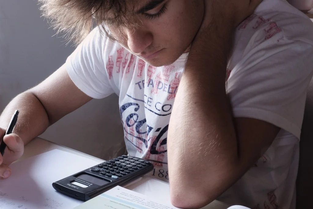 A man is studying with a book and a calculator.