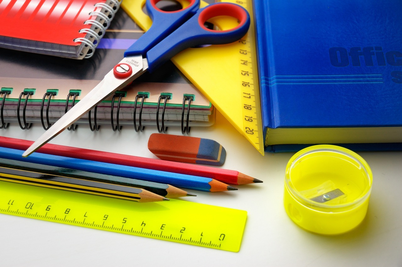 This image shows different classroom items like scissors, a ruler, different pencils, a sharpener, and notebooks.