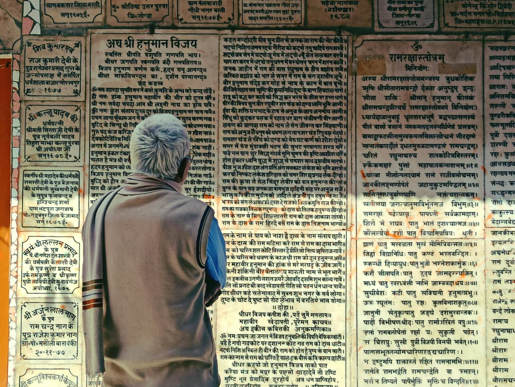 This images shows a man staring at a wall with different texts written in Sanskrit.